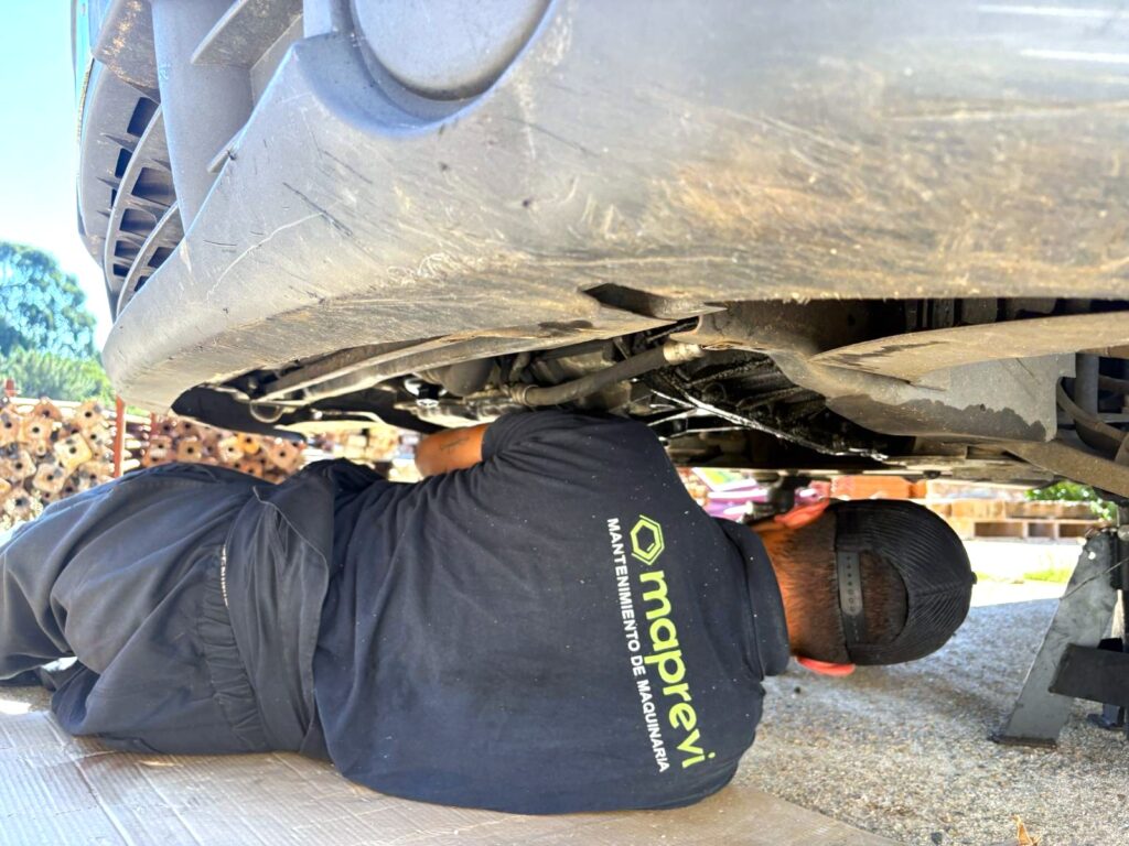 personal de maprevi en el suelo bajo la carrocería de un vehículo industrial reparando una avería